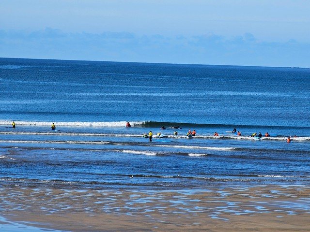 a group of beginner surfers in the shallows in front of the shop trying to catch knee high intermittent waves